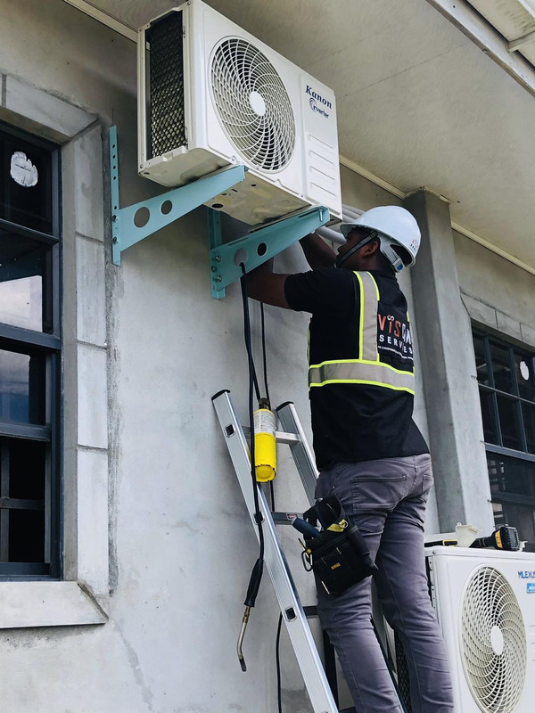 Viscom Services technician mounting an air conditioning outdoor unit